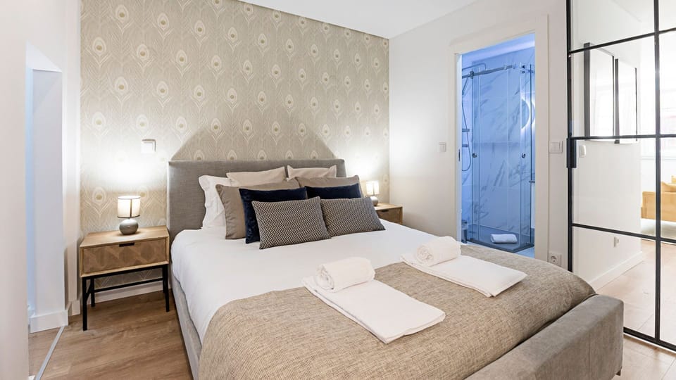 A beautifully decorated bedroom, bathed in natural light, offers a serene escape for a restful night's sleep. The thoughtful details and a glimpse into the modern ensuite bathroom promise comfort and convenience.