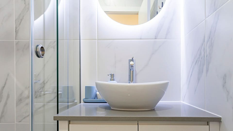 Start your day feeling refreshed in this sparkling modern bathroom, featuring a stylish vessel sink and an illuminated mirror for a spa-like experience.