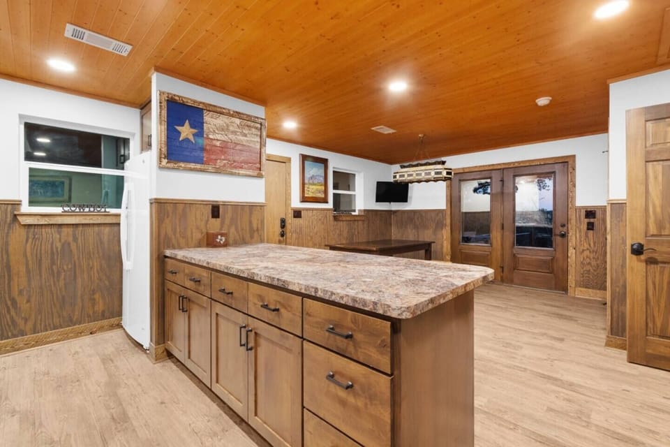 The bunkhouse dining area features a spacious table and seating, and a kitchen island with three pullup stools ideal for enjoying meals together and unwinding after a day of activities. 