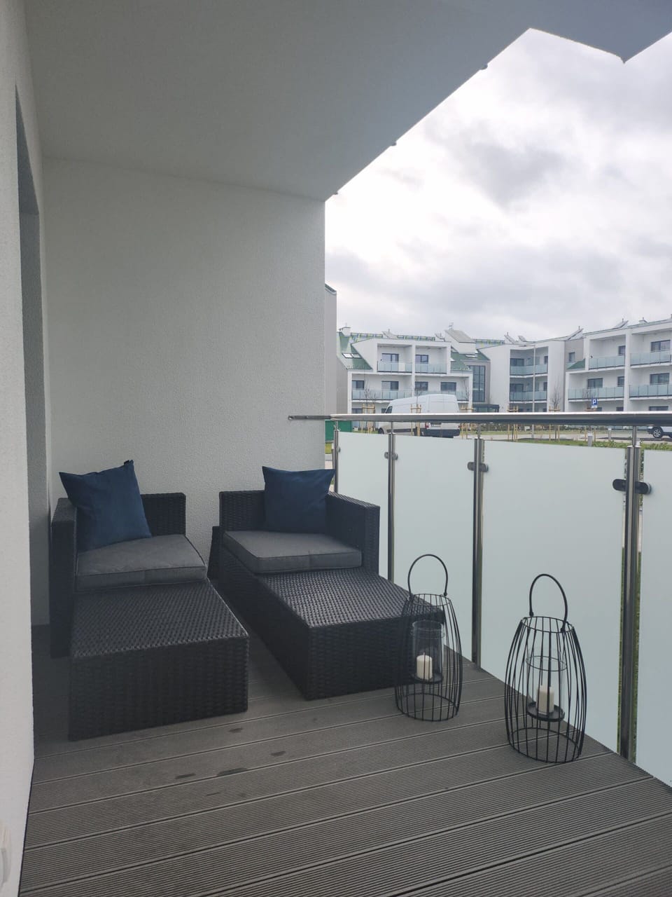 A spacious balcony with outdoor seating and a view of the surrounding buildings.

