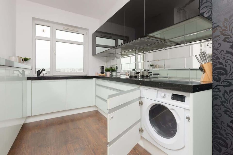 Another angle of the kitchen, featuring a built-in washing machine and plenty of storage space.
