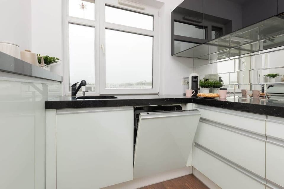 A sleek and bright kitchen corner with white cabinets and a functional layout.
