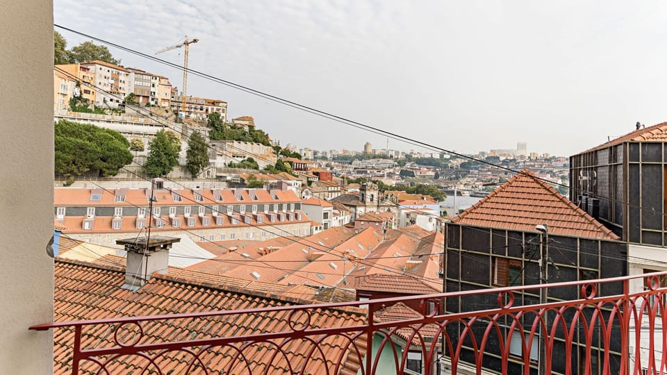Step out onto the balcony and soak in the breathtaking panoramic views over a charming, typical neighborhood with its distinctive rooftops and distant hills. This is the perfect spot to start your day with a coffee or unwind as the city lights begin to tw