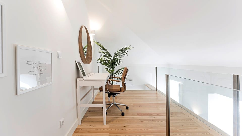 Find your focus in this bright and serene loft workspace, offering a comfortable chair and ample surface for productivity while surrounded by a stylish, airy ambiance. The clever design with a glass railing creates an open, inspiring environment, perfect 