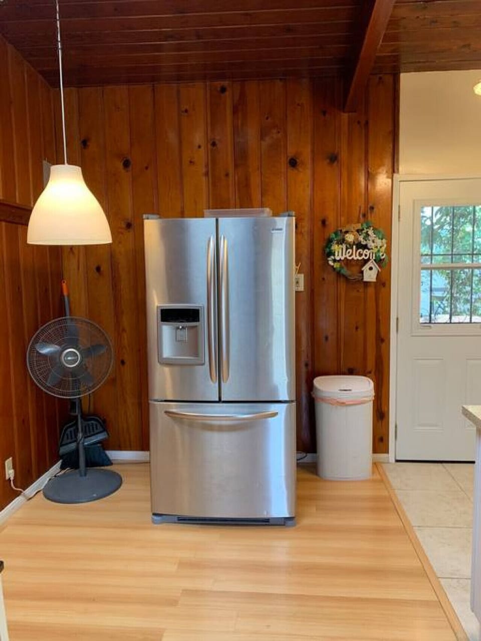 Cozy kitchen corner with a fridge and fan.