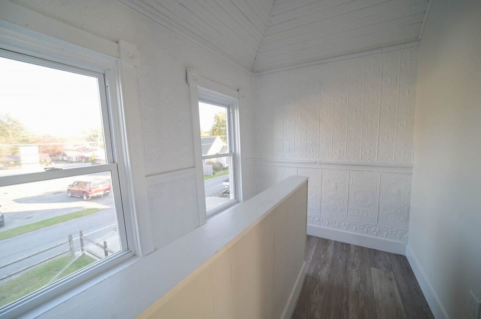 Here is a caption for the hall picture you sent, incorporating the image:  A bright and airy hall with two windows and a wooden floor.