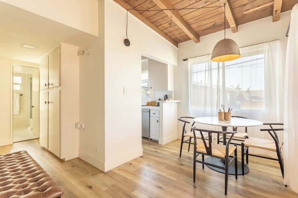 The dining area offers a clear view into a clean,  cozy kitchen equipped with modern appliances.

