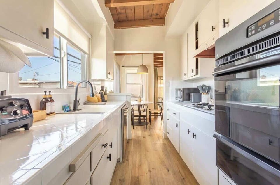 A streamlined galley-style kitchen features clean cabinetry with minimalist hardware and a large window that floods the space with natural light.

