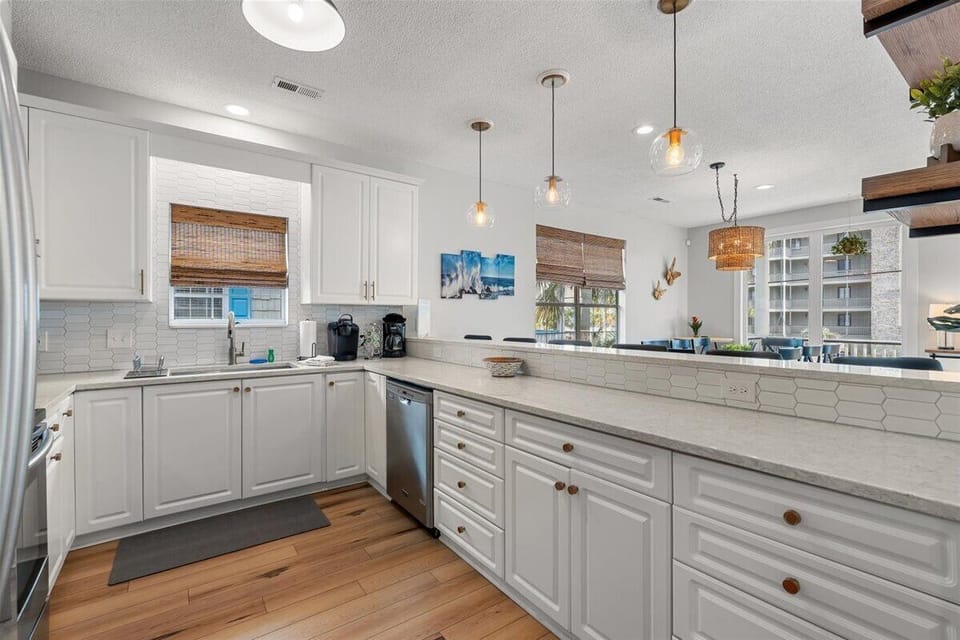 Your gourmet kitchen awaits with crisp white cabinetry, gleaming countertops, and warm pendant lighting creating the perfect space for memorable meals.