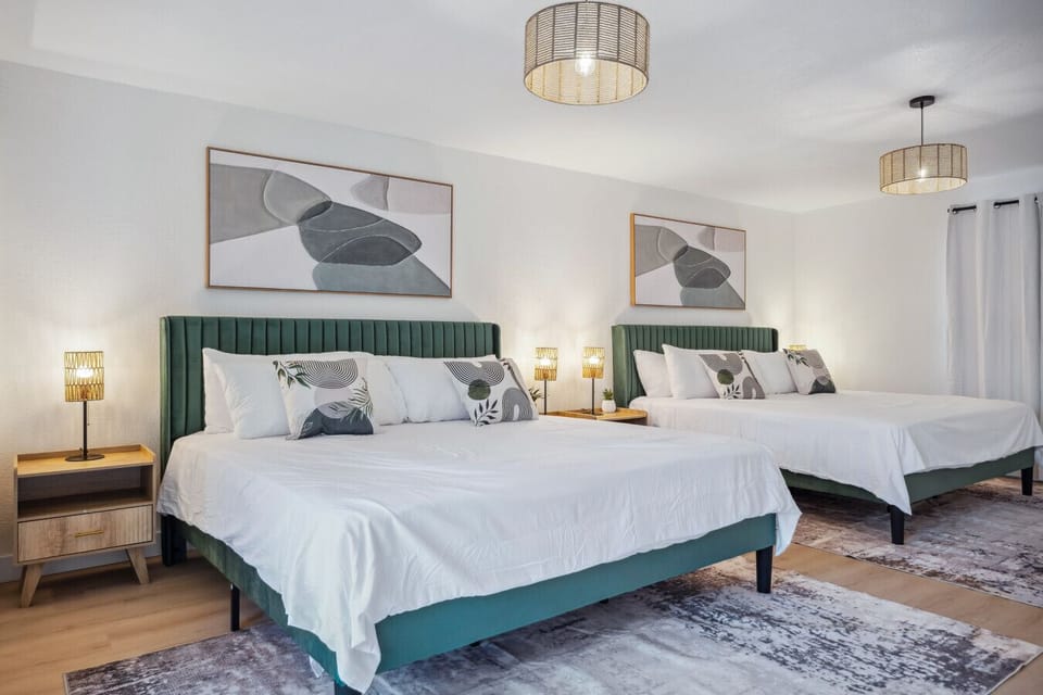Spacious and beautifully styled bedroom with two queen beds and modern decor.
