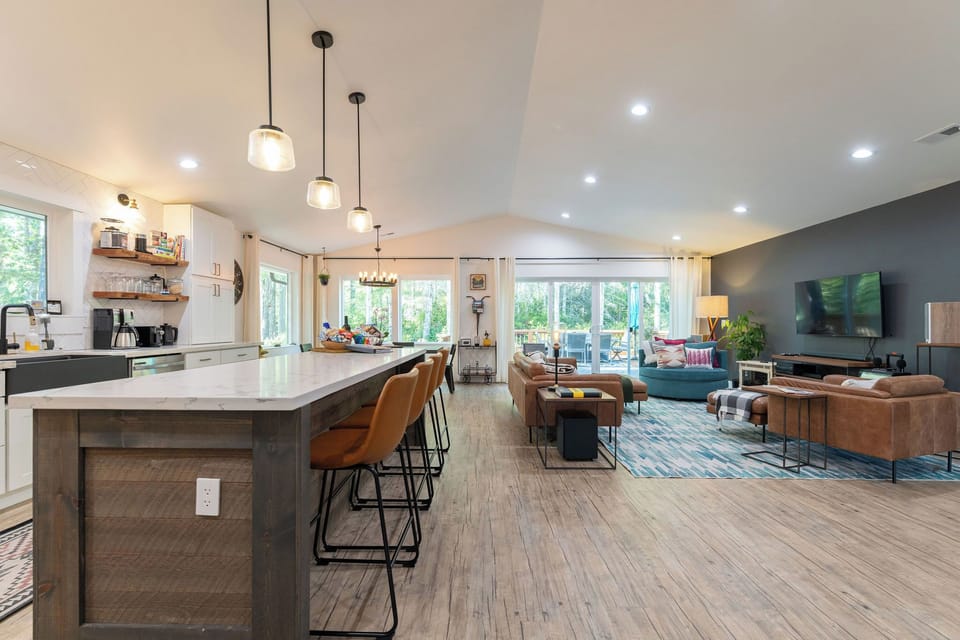 View of the Island and living space looking out onto a private deck and forested yard. 