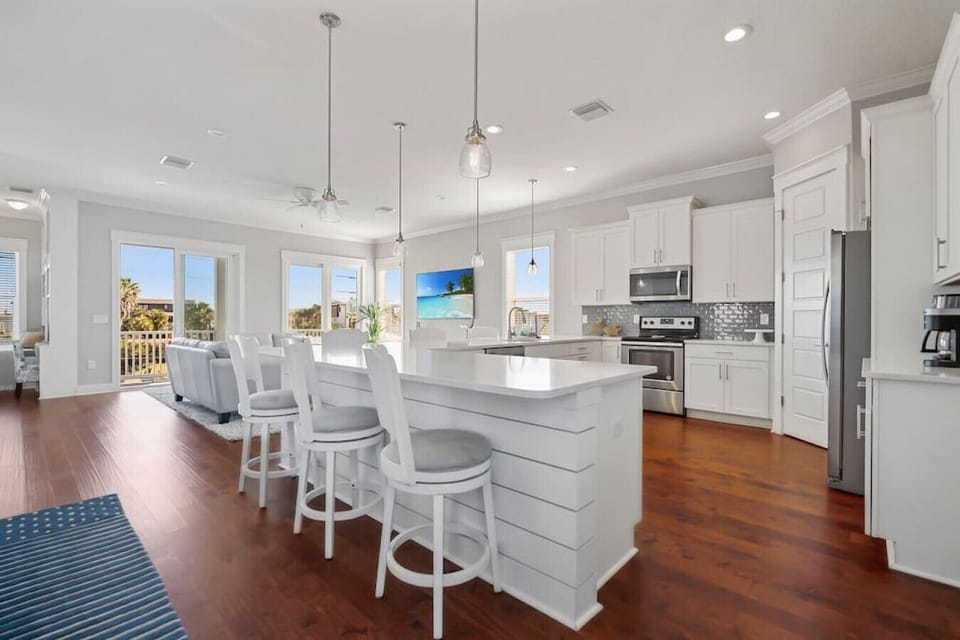 Endless white quart countertop leaves a seat for everyone in this chef`s kitchen.