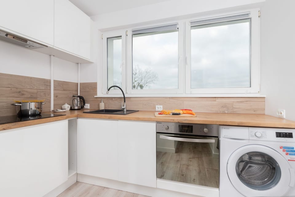 A fully equipped kitchen with a washing machine, ample storage, and plenty of natural light.

