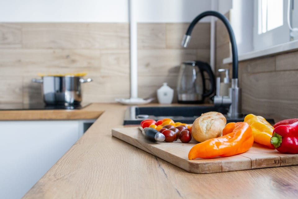 A close-up of the kitchen counter with a sleek black sink, wooden accents, and fresh peppers.

