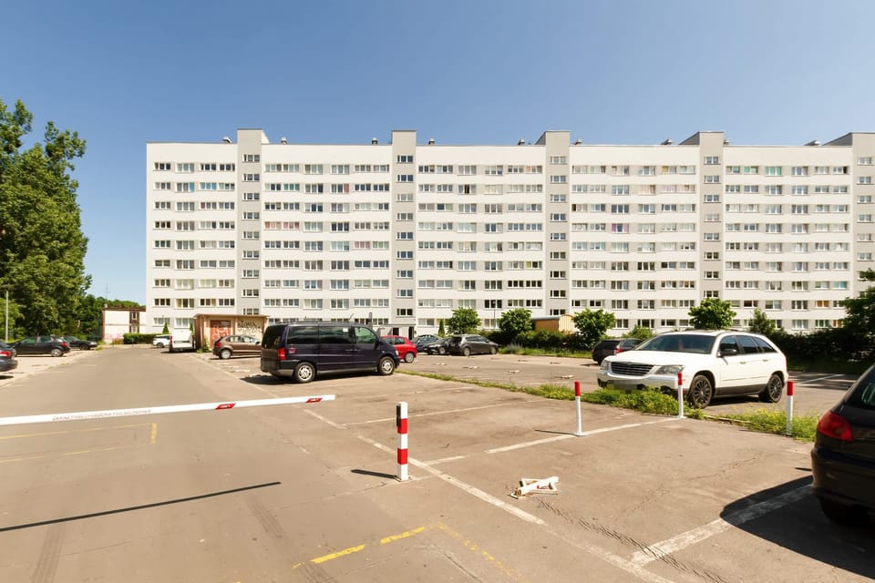 The building’s exterior, showcasing a large residential block and parking spaces.

