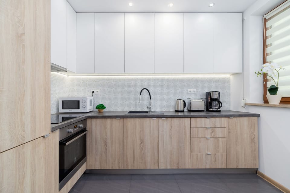 A contemporary kitchen with white cabinets, wooden accents, and built-in appliances.
