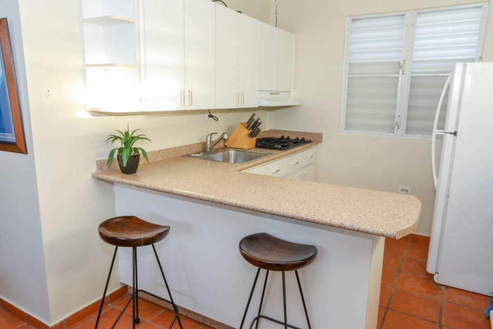 Kitchen with stovetop, toaster oven, microwave, fridge and coffee maker.
