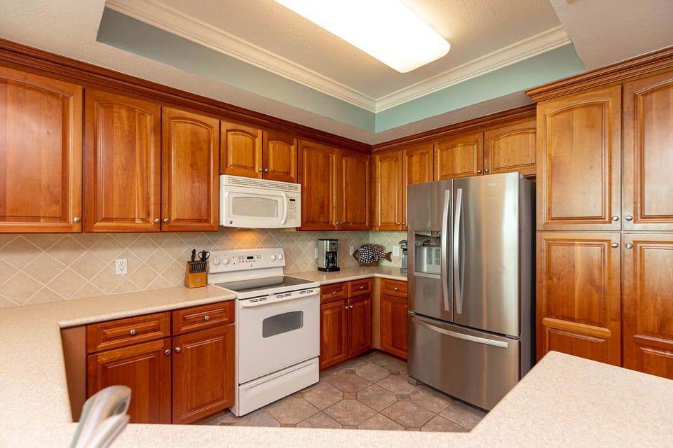 Prepare meals in this spacious kitchen featuring rich wood cabinetry, white and stainless appliances, and ample counter space