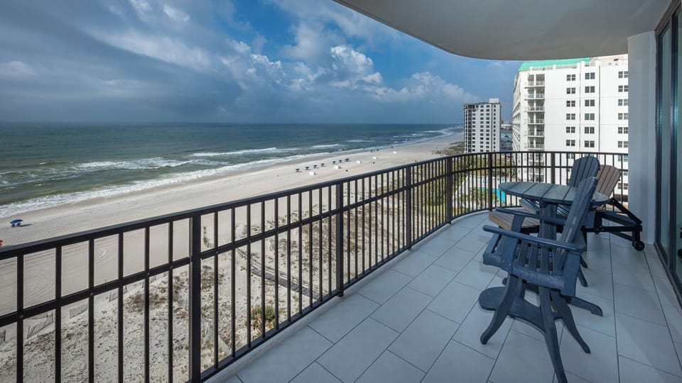 Relax on the balcony with seating, overlooking the beach and gentle waves, perfect for enjoying the view