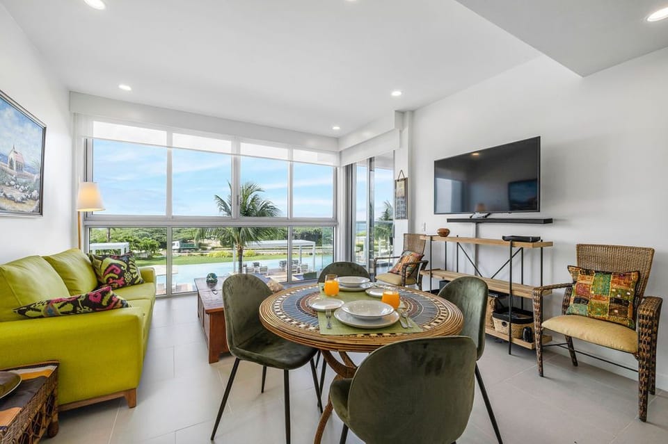 Picture yourself here in this bright, stylish living space where palm trees frame your pool and ocean views. Relax on vibrant seating while you sip morning juice at your cozy dining table.