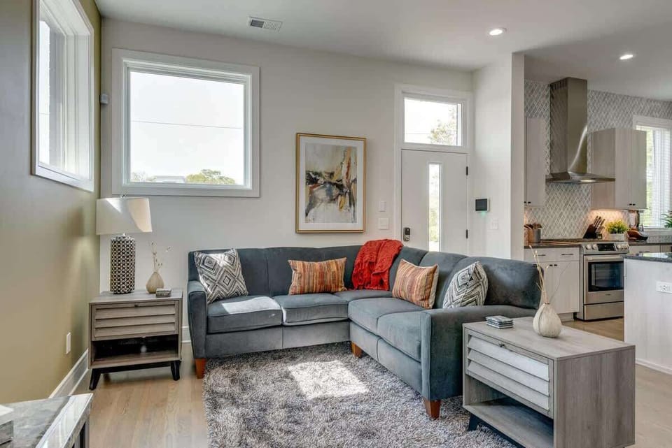 Relax in style: Our bright, open-concept living room features a custom designer sectional and 70” Smart TV.
