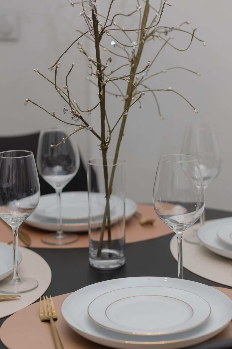 A close-up of a table setting with elegant dinnerware and a modern centerpiece.

