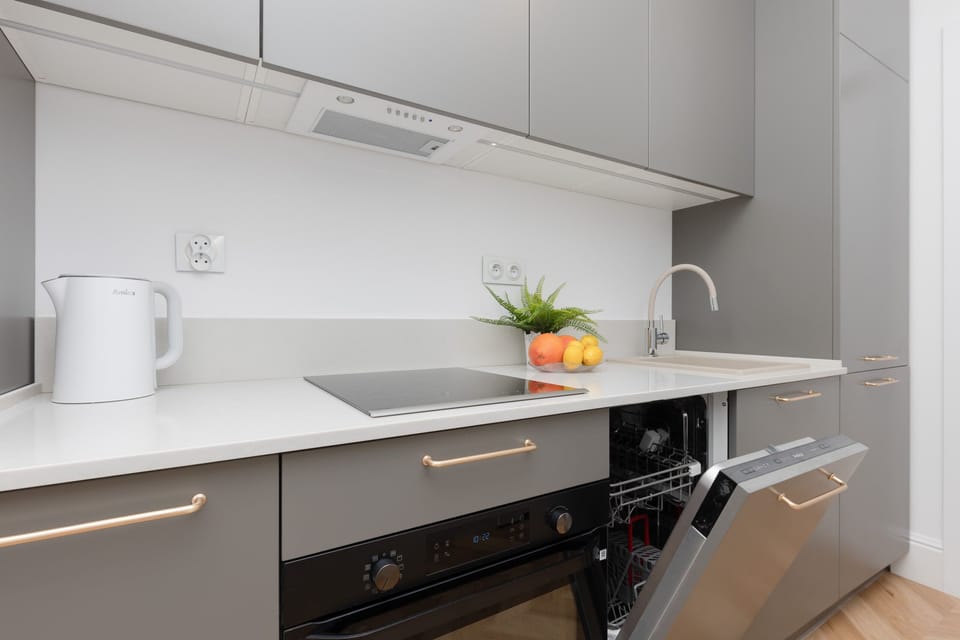 A modern kitchen with gray cabinetry, a sleek countertop, and a built-in dishwasher.


