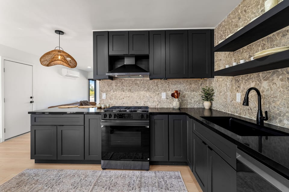 Cook with ease in the sleek, fully equipped kitchen, featuring a gas range, open shelving, and generous prep space.