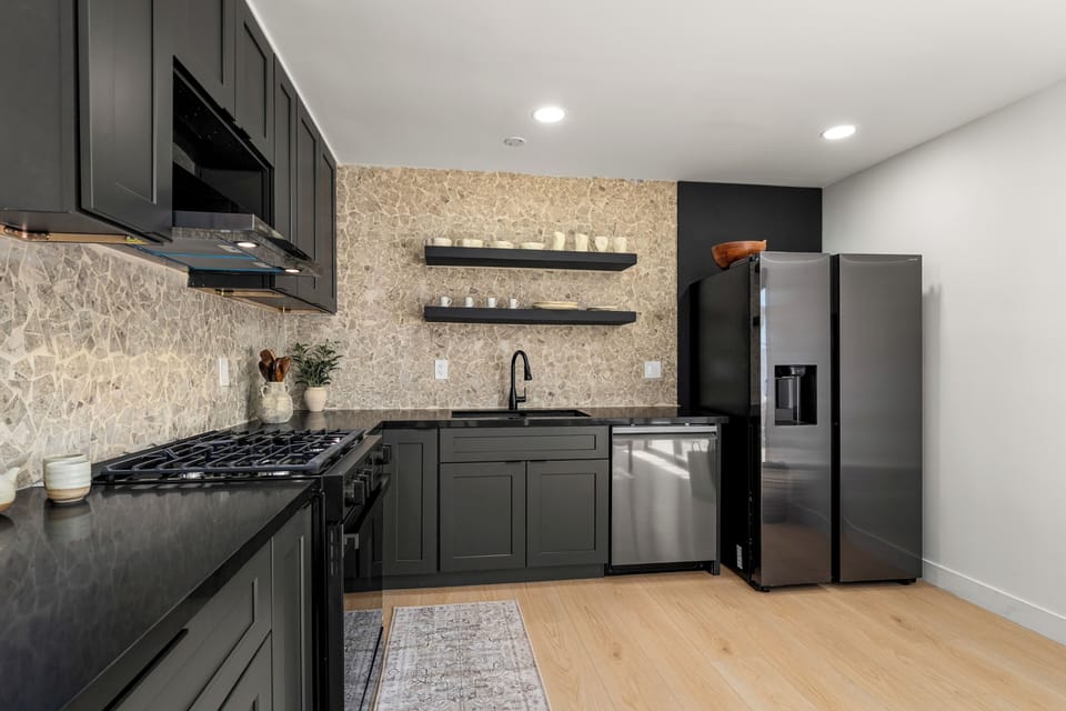 Cook with ease in the sleek, fully equipped kitchen, featuring a gas range, open shelving, and generous prep space.