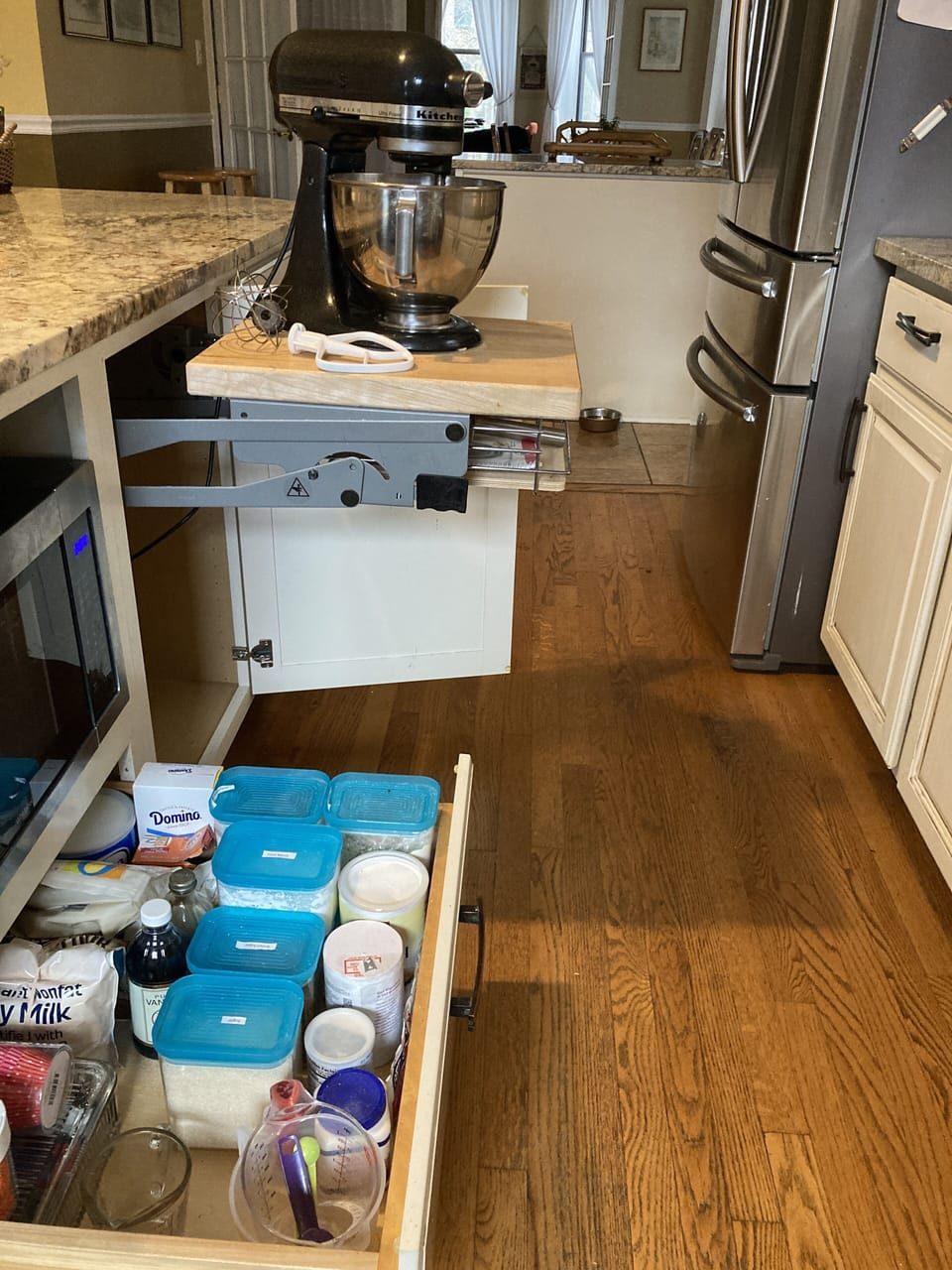 Kitchen Aid mixer in pop-up stand and lots of baking supplies.
