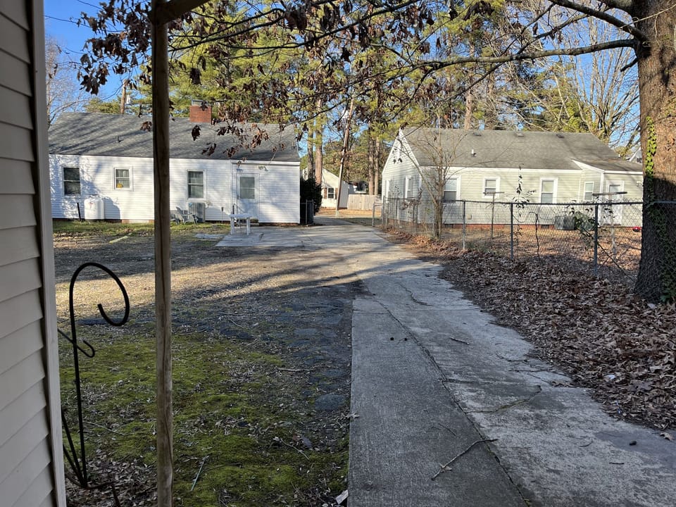 Backyard view of shared driveway, and the back of the home, were yellow markers are placed for backyard parking that won’t obstruct the driveway 