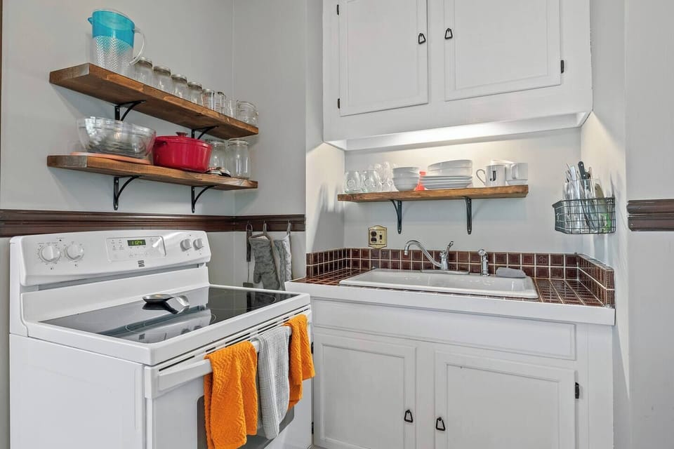 Kitchen with sink, stove and oven. Dishwasher is to the right near the fridge.