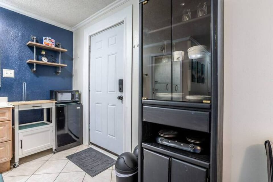 Kitchen with a microwave, small fridge, two-burner stove, and a cabinet for dishes.