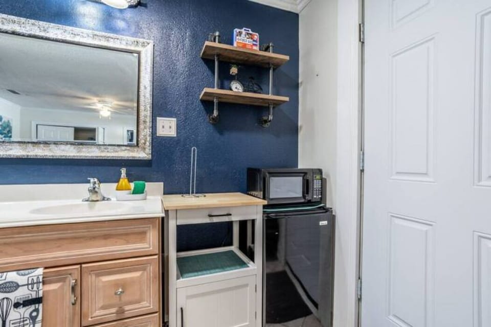 Kitchen with a microwave, small fridge, two-burner stove, and a cabinet for dishes.