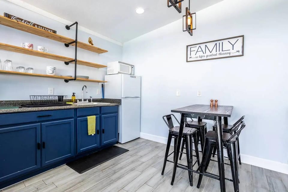 Kitchen and dining area with a small stove, oven, and refrigerator. Cabinets provide ample storage. A wooden dining table with chairs sits nearby, creating a cozy space for meals.