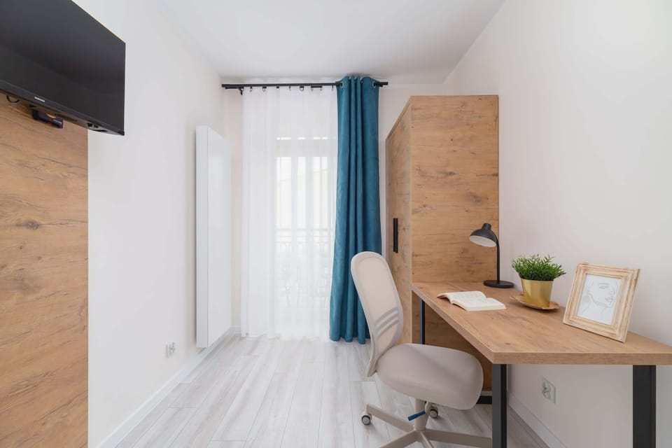 A workspace by the window with a wooden desk, chair, and decorative touches.
