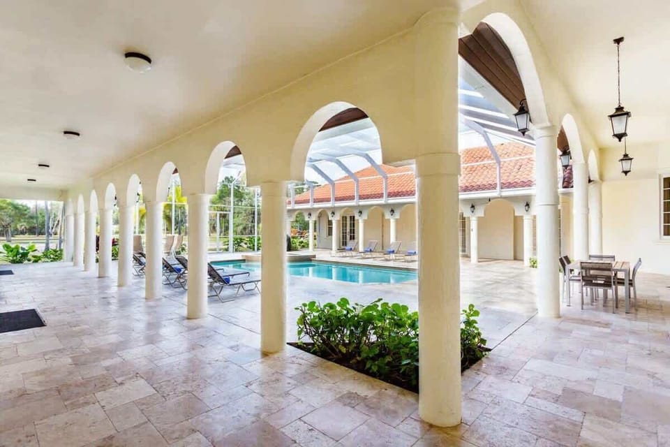 Outdoor area with pool, dining tables, lounge chairs and a grill