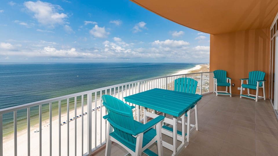 Relax on turquoise chairs at the balcony table, feeling gulf breezes while watching the beachfront below