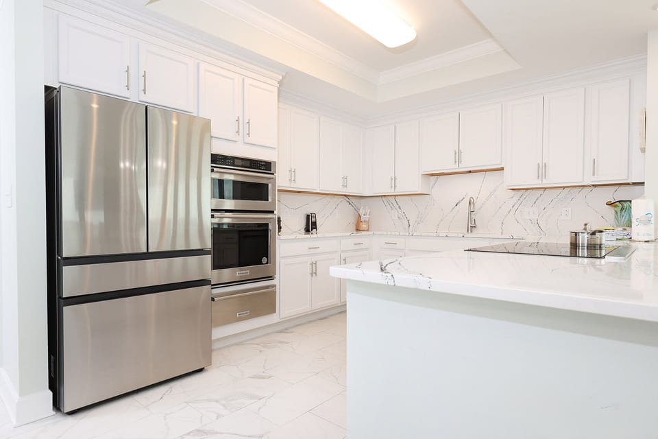 Cool marbled counters accent this elegant kitchen with modern stainless appliances and sleek cabinetry