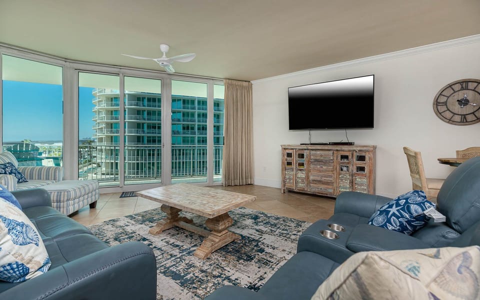 The living area features a large TV, a stylish coffee table, and a cozy seating arrangement with a beautiful view