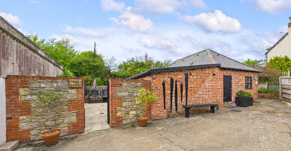 Front exterior of The Cote at Little Upton Farm, showing traditional barn-style façade and surrounding countryside.