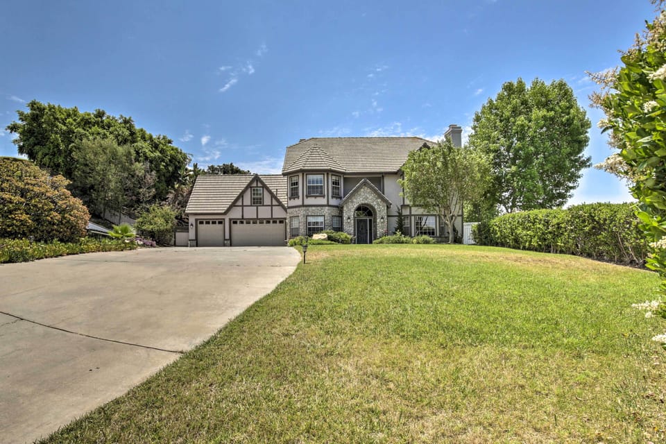 Front view with large driveway, green lawn, and elegant Tudor-style home!