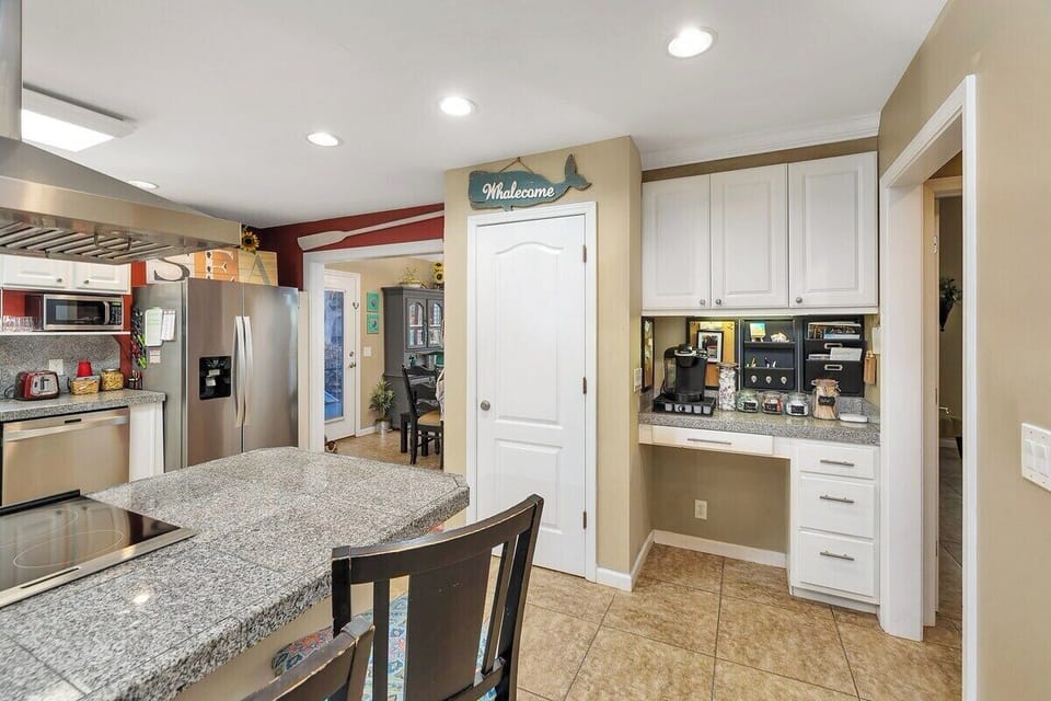 Open kitchen with granite island, appliances, and white cabinets