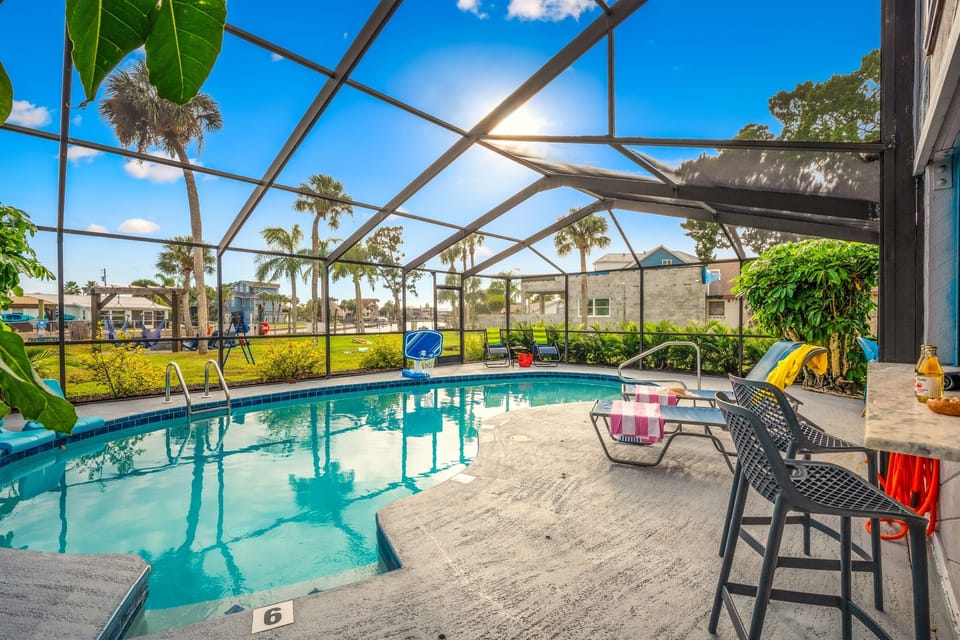 Private heated saltwater pool with spacious screened lanai, poolside bar, and open backyard views.