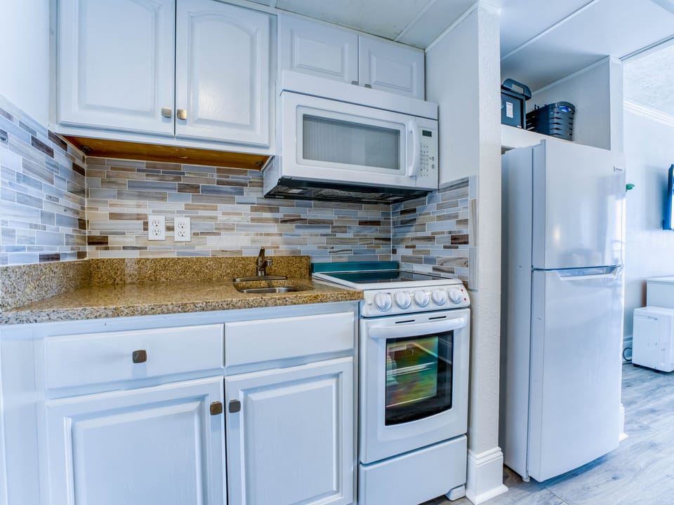 Fully equipped kitchenette with oven, electric range, microwave, sink, and more.