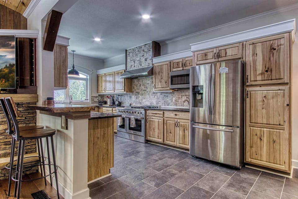 A beautifully designed kitchen with wooden cabinetry, stainless steel appliances, and a cozy breakfast bar.