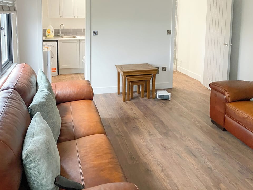 2 leather sofas and wood burner within the living area | The Cabin, Nutbourne, near Chichester