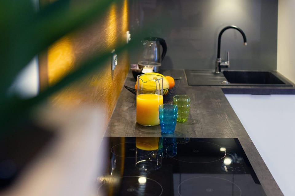 A close-up of a black countertop with a fruit bowl and drinks, showcasing the kitchen's functionality.
