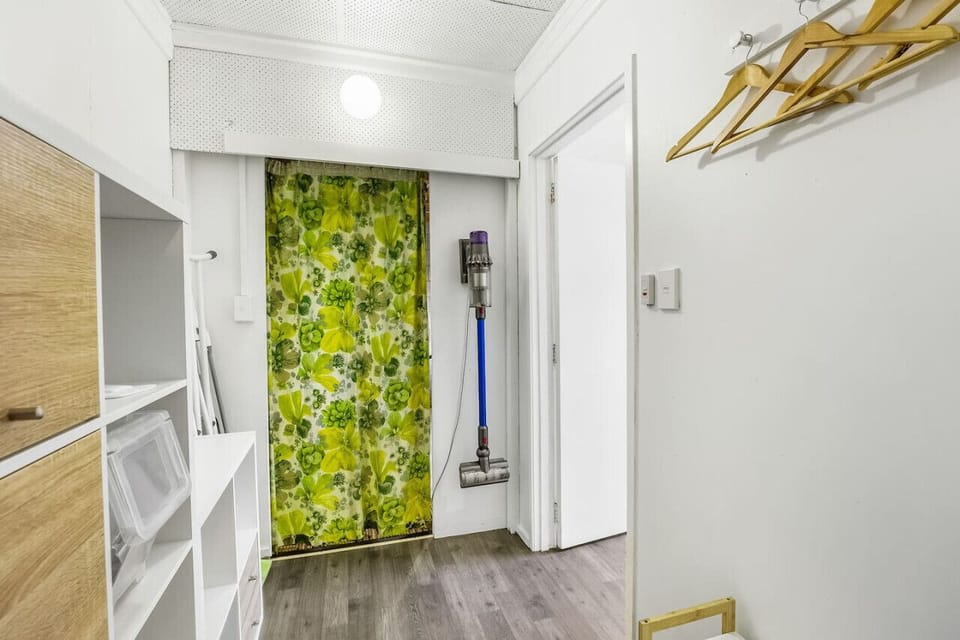 Where the Dyson vacuum, ironing board, and drying rack are stored in the storage area by the laundry.