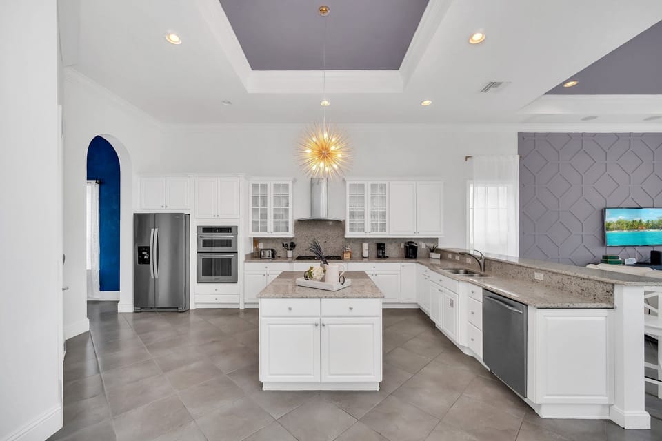 The open kitchen features modern appliances like a sleek 2-door fridge, oven, coffee maker, and more. With a central table at your disposal, meal preparation becomes a seamless and enjoyable experience.